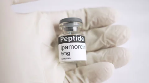 Gloved hand holding an ipamorelin peptide vial Видео 343617090
