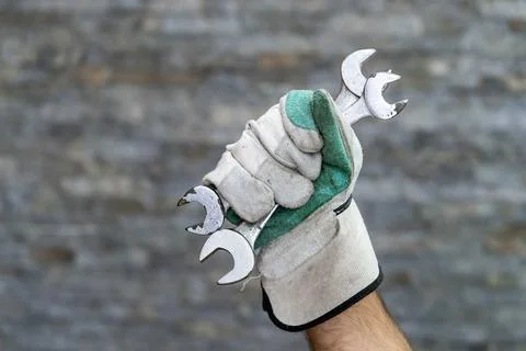Gloved hand holding multiple open end wrenches Stock Photos