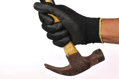 Gloved hand holding a rusty claw hammer isolated background. Stock Photos