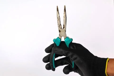Gloved hand holding a rusty long nose pliers isolated background. Stock Photos