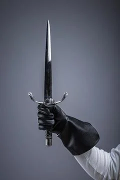 Gloved Hand Holding Sharp Medieval Dagger. Close-up of a hand in leather gl.. Stock Photos
