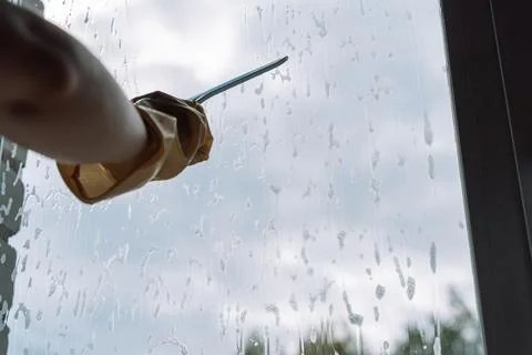 Gloved hand holding a squeegee across the upper window Foto stock