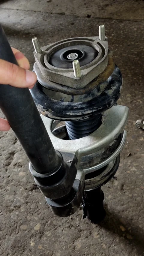 A gloved hand holds a compressed car strut with clamps Stock Footage 335834876