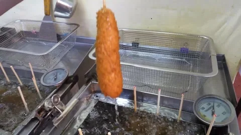 Gloved Hand Lifting Freshly Fried Crispy Corn Dog From Deep Fryer Video stock 343587656
