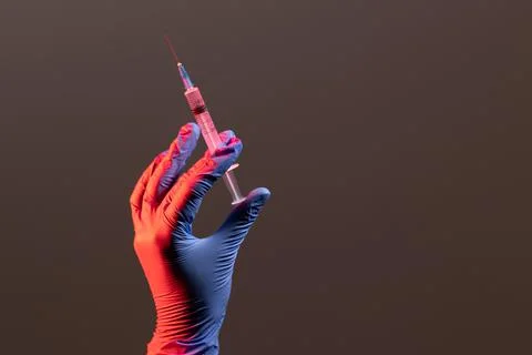 The gloved hand is located on the left side and holds a syringe. The concept of Stock Photos