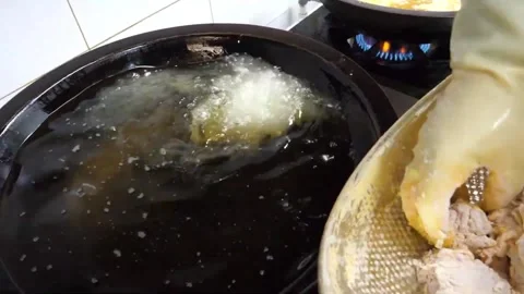 Gloved Hand Lowering Battered Chicken Piece into Hot Deep Frying Oil Pan Video stock 343027769
