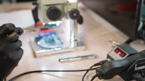 Gloved Hand Operating Soldering Station with Microscope and Circuit in Lab Stock Footage 284359472