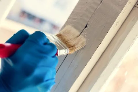 A gloved hand paints a window frame. Repair in the house. Services painter Stock-Fotos