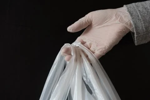 A gloved hand passing a package. The concept of contactless delivery. Securit Stock Photos