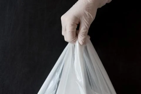 A gloved hand passing a package. The concept of contactless delivery. Security. Stock Photos