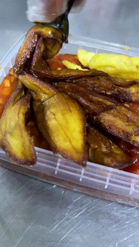 Gloved hand placing fried eggplant slices into a plastic takeaway container Video stock 309655926