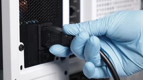 Gloved hand plugging power cable into PSU socket on the back of white compu.. Stock Footage 305673170