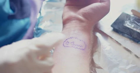 A gloved hand points to the pattern on the skin. Get a tattoo on your wrist Stock Footage 154964778