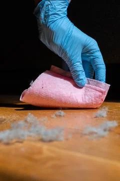 Gloved hand preparing to wipe dust from a household surface Foto stock