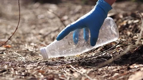 A gloved hand removes a plastic bottle from the ground Stock Footage 170830708