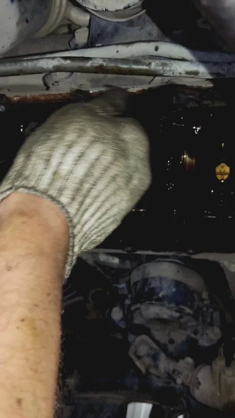 Gloved hand scraping old gasket from car engine bottom under vehicle Stock Footage 336560104