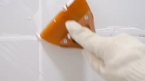 Gloved hand seal the seams between ceramic tiles with rubber spatula, repair Stock Footage 231099667