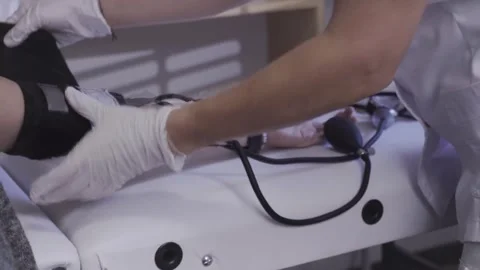 Gloved hand securing blood pressure cuff on patient arm 스톡 동영상 342821636