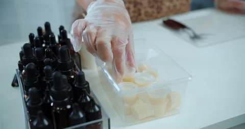 Gloved hand selecting lipstick base at beauty workshop Stock Footage 314601306