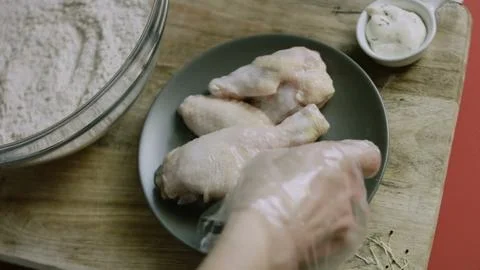 Gloved hand selecting a raw chicken wing Stock Photos