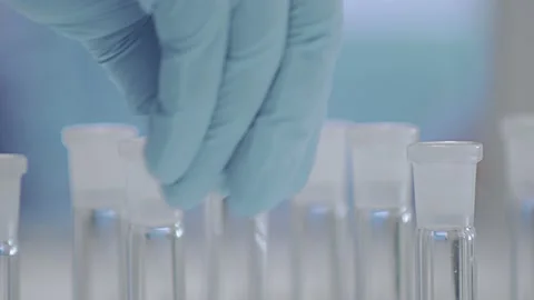 A gloved hand shakes sample tubes in the laboratory. Stock Footage