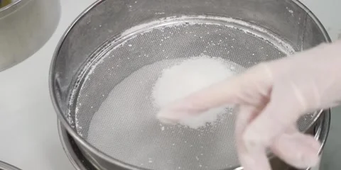 Gloved Hand Sifting White Powder Ingredient Through Fine Mesh Metal Sieve Stock Footage 343589237