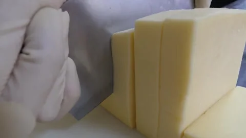 Gloved Hand Slicing Block Cheese with Large Knife on Cutting Board 動画素材 343587525