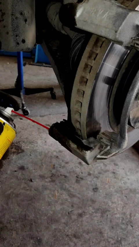 Gloved hand spraying cleaner onto a rusty car brake caliper Stock Footage 333701792