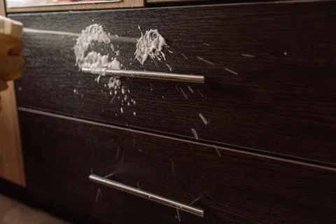 Gloved hand spraying foam onto a dark drawer front 스톡 사진