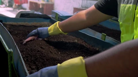 Gloved Hand Stirring Dry Soil to Prepare Organic Compost Stock Footage 346622799