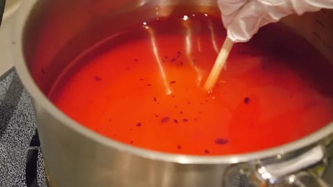 Gloved Hand Stirring Red Liquid in a Large Pot Stock Footage 345292555