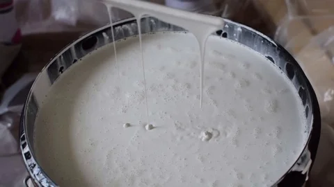 A gloved hand is stirring white paint Stock Footage 126321750