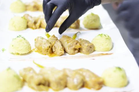 A gloved hand takes cabbage meatloaf sprinkled with sauce, close-up, cookin.. Stock Photos