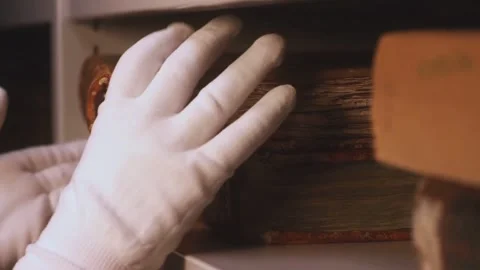 Gloved Hand Taking Ancient Book from Shelf Museum Library Close Up 動画素材 331774093