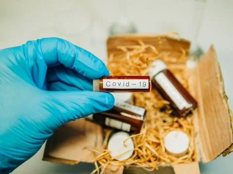 Gloved hand taking a blood sample from a box for analysis Stock Photos