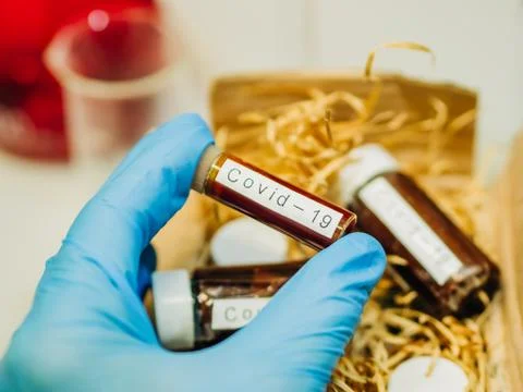 Gloved hand taking a blood sample from a box for analysis Stock Photos