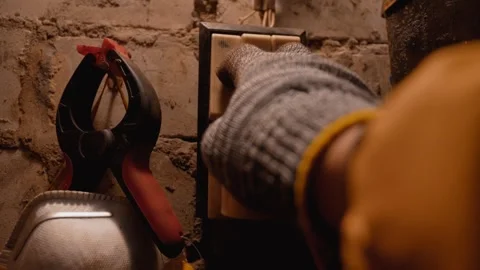 Gloved hand turning on old light switch in a basement Video stock 330081436