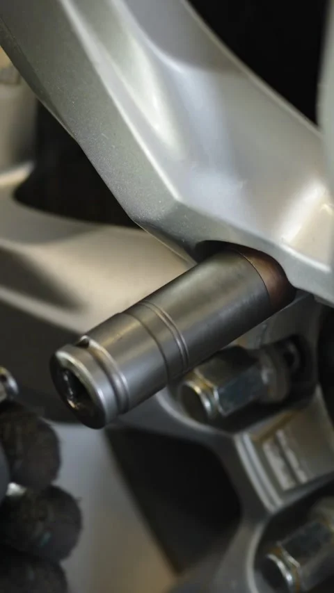 A gloved hand uses a socket wrench to tighten a lug nut on a silver car Stock Footage 336710834