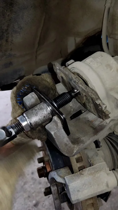 Gloved hand uses a spreader tool to compress brake piston 動画素材 333701803