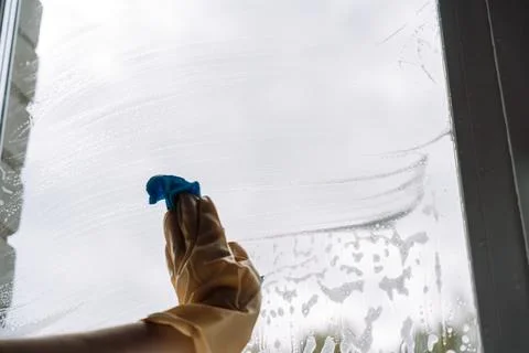 Gloved hand wiping the lower window with a blue cloth Foto stock