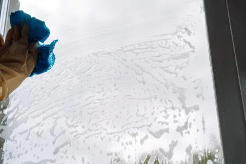 Gloved hand wiping the upper left window with a blue cloth Foto stock