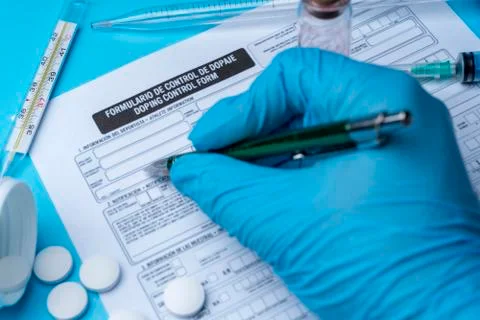 A gloved hand writes on a doping control form. Foto stock