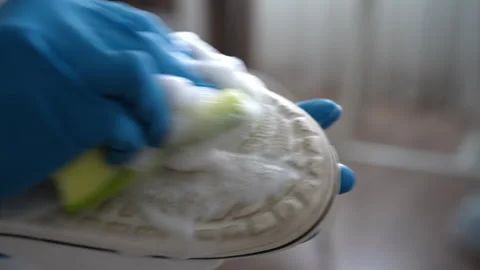 Gloved hands applying cleaning foam onto sole of white shoes using small sponge Stock Footage 301394605