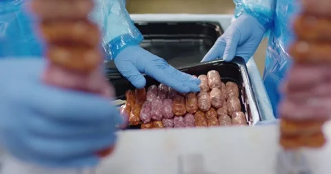 Gloved hands arranging small raw sausages on wooden skewers in black plastic Stock Footage 339961485