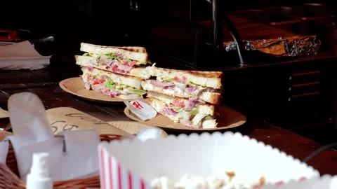 Gloved hands assembling stacked sandwich tower, deli cook plating layered Stock Footage 329315042