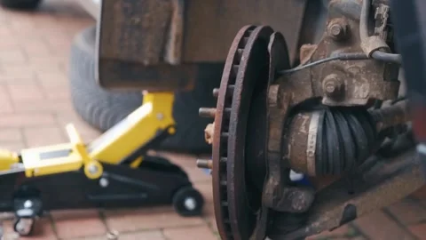Gloved hands attempting removing seized old brake disc from wheel hub Stock Footage 343509643