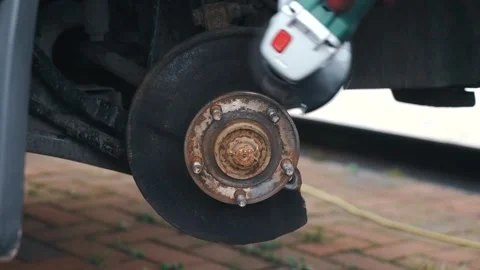 Gloved hands cleaning rusted wheel hub with angle grinder and wire brush Stock Footage 337417758
