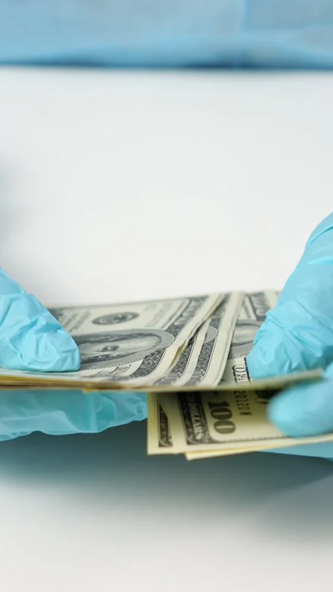 Gloved Hands Count Dollar Bills Steadily Over White Surface Indoors. Medical Stock-Footage 346989328