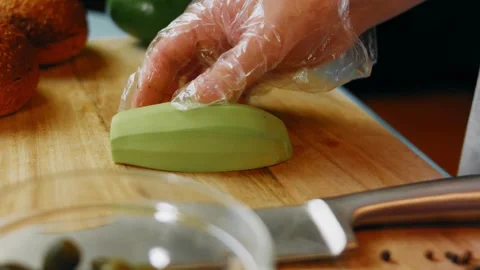 Gloved hands creating thin avocado slices, 4K Stock Footage 341120581