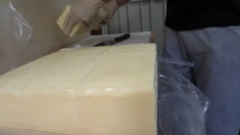 Gloved Hands Cutting Large Block of Cheddar Cheese Video stock 343587581